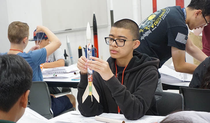 Student makes a rocket at an engineering summer camp for school children.