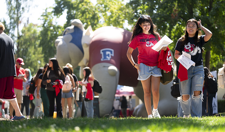 Fresno State students walk near large Bulldog inflatable on campus.