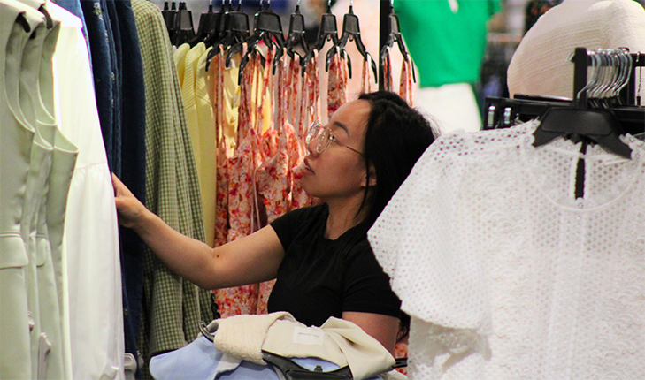 Student looking at dresses in department store